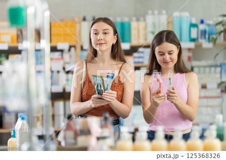 Woman with daughter choosing toothbrush in pharmacy Woman with daughter choosing toothbrush in pharmacy 125368326