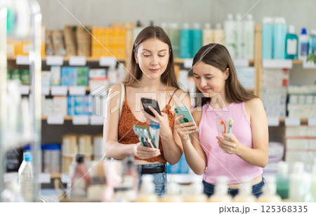 Daughter and mother in summer clothes scans code on toothbrush kit to check expiration date 125368335