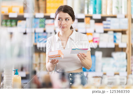 Young woman chooses pills at pharmacy 125368350