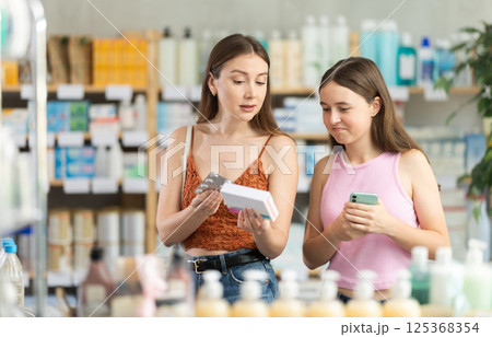 Woman with daughter choosing pills in pharmacy 125368354
