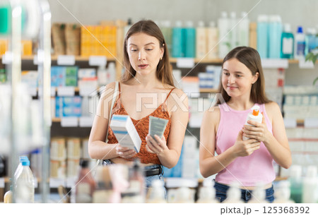 Woman with daughter choosing cream in pharmacy 125368392