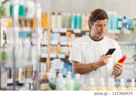Adult man scanning qr code of sunscreen 125368474