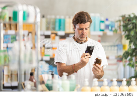 Man scans for mobile medicinal syrup in pharmacy Man scans for mobile medicinal syrup in pharmacy 125368609