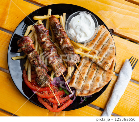 Shishqebap with French fries, tomatoes and pita bread. Albanian cuisine 125368650
