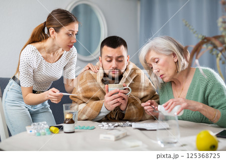 Elderly mother and a young wife give pills and medicines to her husband during illness Elderly mother and a young wife give pills and medicines to her husband during illness 125368725
