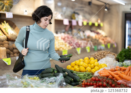 Woman carefully selects red bell peppers in grocery supermarket Woman carefully selects red bell peppers in grocery supermarket 125368732