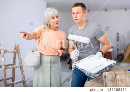 Senior woman discussing work details with teenager boy in constrcuction site 125368852