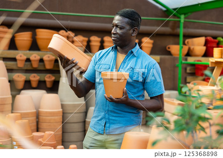African american man choosing pots for flowers and trees in gardening market 125368898