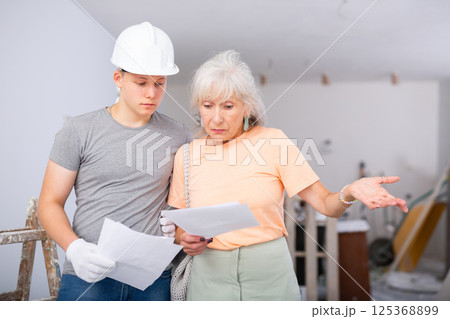 Grandmother and grandson are discussing the drawings of apartment room being renovated 125368899