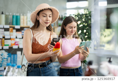 Woman with daughter scanning qr code of sunscreen 125368917
