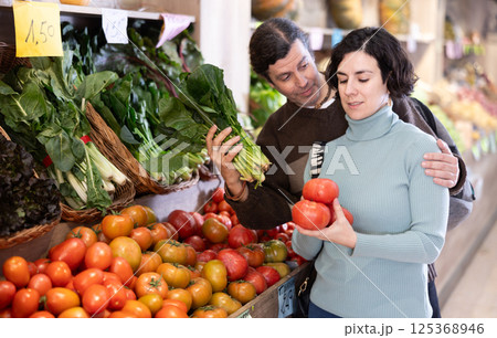 Husband and wife choose ripe tomatoes 125368946