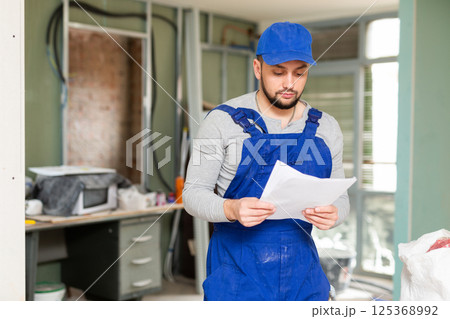 Foreman reading papers on indoor construction site Foreman reading papers on indoor construction site 125368992