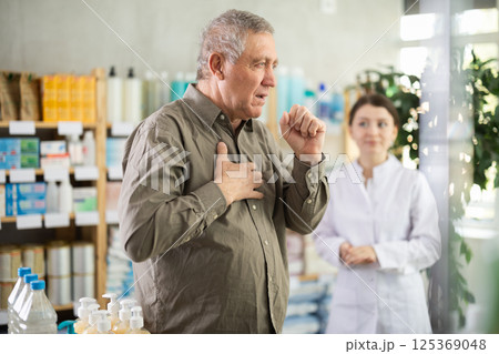 Man with cough choosing pills with help of pharmacist 125369048