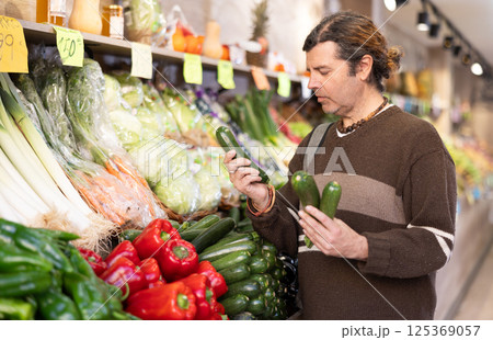 Man choosing zucchini at the counter Man choosing zucchini at the counter 125369057