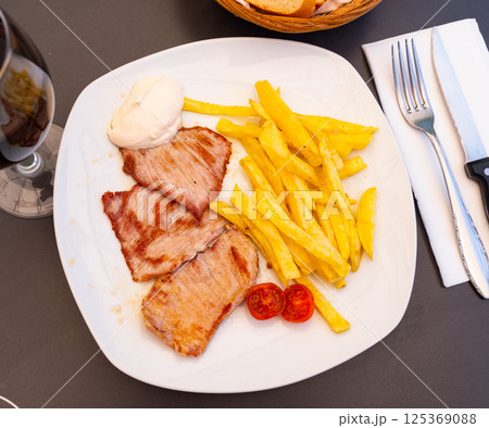 On plate are pieces of fried pork tenderloin,garnished with French fries. On plate are pieces of fried pork tenderloin,garnished with French fries. 125369088