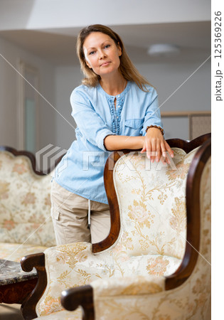 Positive woman standing near sofa at home Positive woman standing near sofa at home 125369226