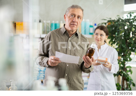 Man choosing pills with help from pharmacist Man choosing pills with help from pharmacist 125369356