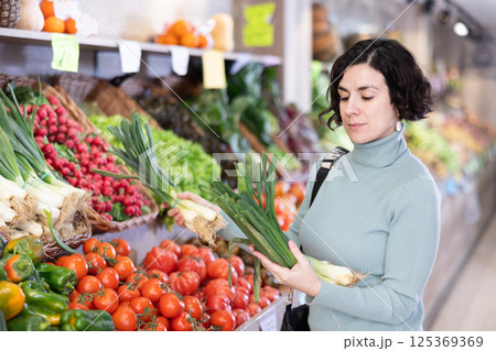 Adult woman choosing green onions in vegetable shop 125369369