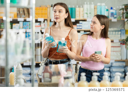 woman with a child choosing an oral mouthwash at a pharmacy 125369371