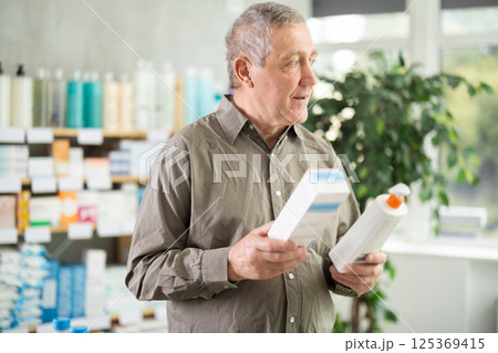 Senior man buys cream at pharmacy 125369415