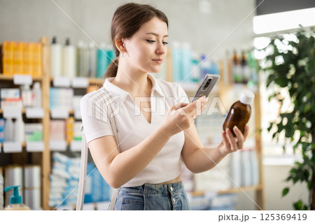 Woman scanning cough syrup on her phone Woman scanning cough syrup on her phone 125369419