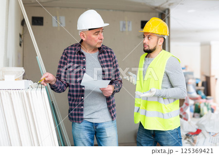 Foreman and confused builder counting building materials 125369421