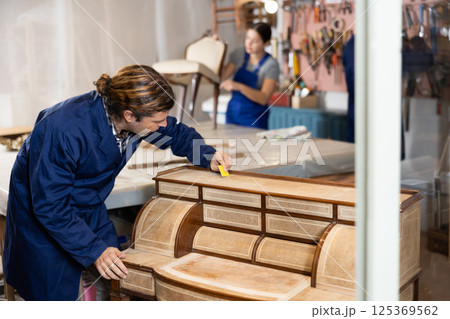 Male furniture maker sanding vintage commode in workshop 125369562