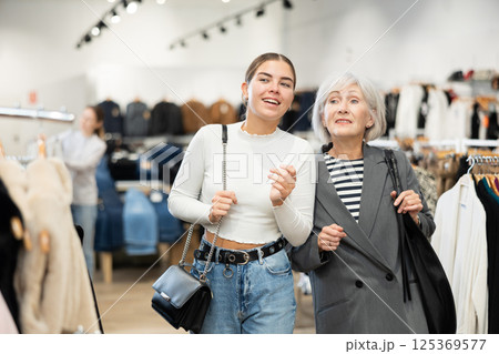 Two women customers watching large stock of clothes in clothing store 125369577