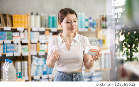 Girl in summer clothes looking for medicine in pharmacy 125369612