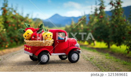 Colorful scene depicts toy truck transporting fresh apples and fruits from farm to market, cartoon-like characters made from knitted wool toys, animation concept for kids media and branding. 125369681