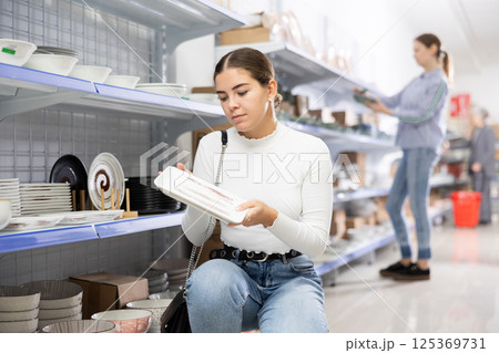 Young girl choosing square ceramic Asian style plates in store 125369731