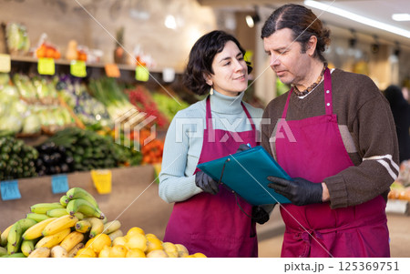 Man and woman sellers taking inventory in vegetable shop 125369751