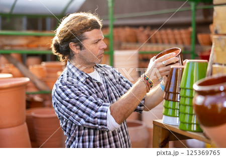 Portrait of man choosing pots for flowers and trees in gardening market Portrait of man choosing pots for flowers and trees in gardening market 125369765