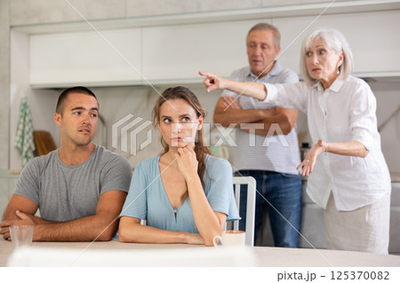 Elderly parents make claims to young couple in kitchen 125370082
