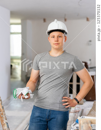 Portrait of a fifteen-year-old teenager with a roller and a paint tray in his hands Portrait of a fifteen-year-old teenager with a roller and a paint tray in his hands 125370132