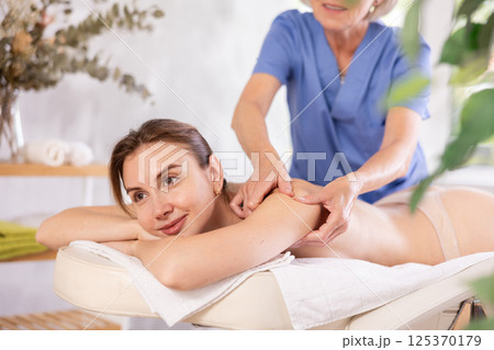 Young woman relaxing in spa center during professional back massage Young woman relaxing in spa center during professional back massage 125370179