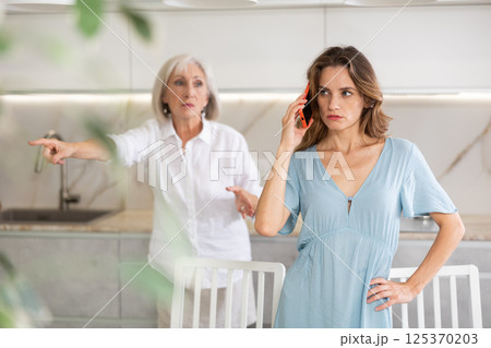 Elderly mother kicks her out of house and yells at her adult daughter while she is talking on mobile phone 125370203