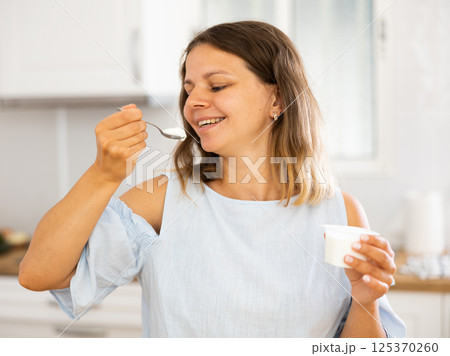 Light breakfast of yogurt and apples for young happy girl in modern kitchen 125370260