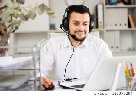 Portrait of smiling call center worker with headphones 125370294