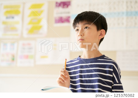 ノートと鉛筆を持って考え中の高学年男子小学生 125370302
