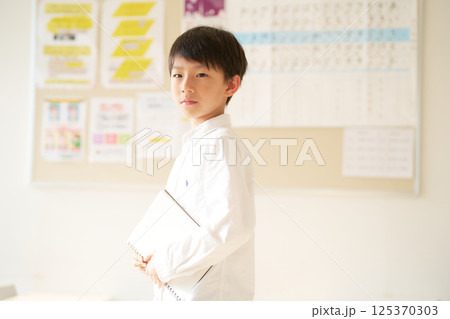 ノートを持って立つ男の子｜低学年男子のポートレート 125370303