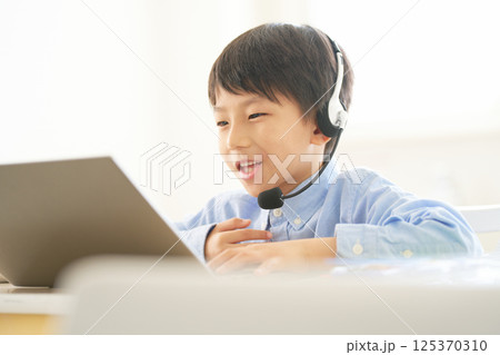 PCの画面を見ながら笑顔で会話する小学生の男の子|オンライン学習 イメージ PCの画面を見ながら笑顔で会話する小学生の男の子|オンライン学習 イメージ 125370310