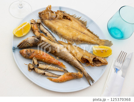 On white background, there is plate with fried fish of different varieties On white background, there is plate with fried fish of different varieties 125370368