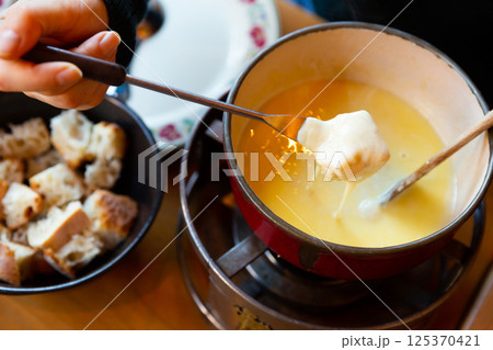 Fondue Savoyarde is a popular dish of the Savoy region 125370421