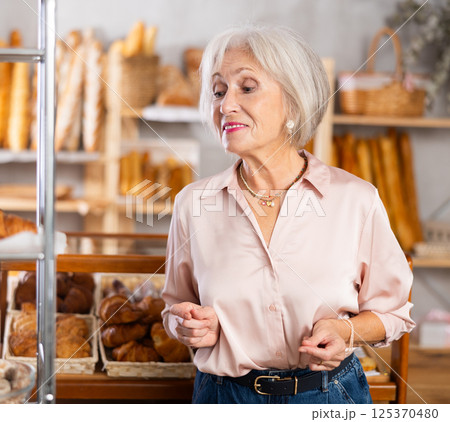 Mature female customer choosing bread and other delicious pastries in bakery Mature female customer choosing bread and other delicious pastries in bakery 125370480