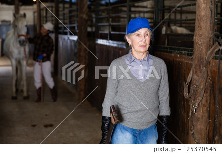 Portrait of mature woman in stable with hay pitchfork 125370545