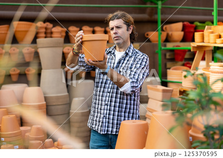 European man chooses flower pots for indoor plants European man chooses flower pots for indoor plants 125370595