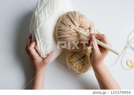 Child hands knitting with yarn and crochet hook on white background 125370958