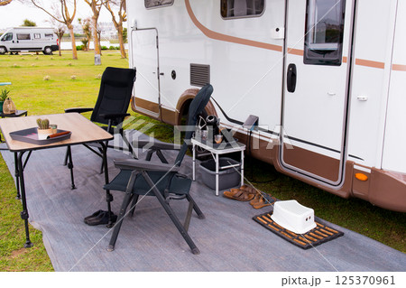 Cozy outdoor rv camping setup with chairs and table on a carpeted mat Cozy outdoor rv camping setup with chairs and table on a carpeted mat 125370961