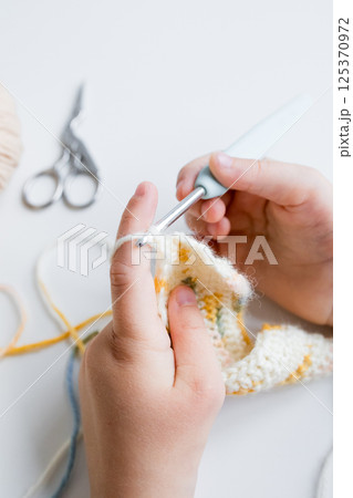 Close up of hands crocheting a colorful pattern with crochet hook and yarn Close up of hands crocheting a colorful pattern with crochet hook and yarn 125370972